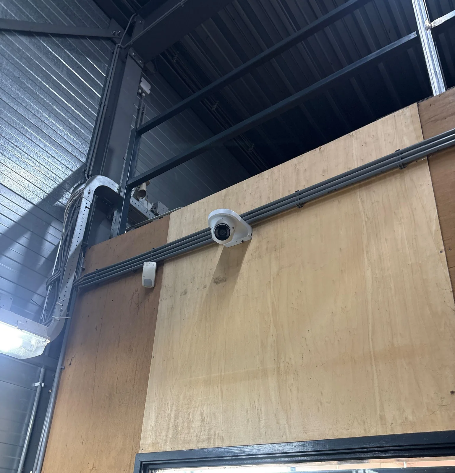 Witte VIGI-turret op een houten wand hoog in een bedrijfshal, met een kabelgoot erlangs
