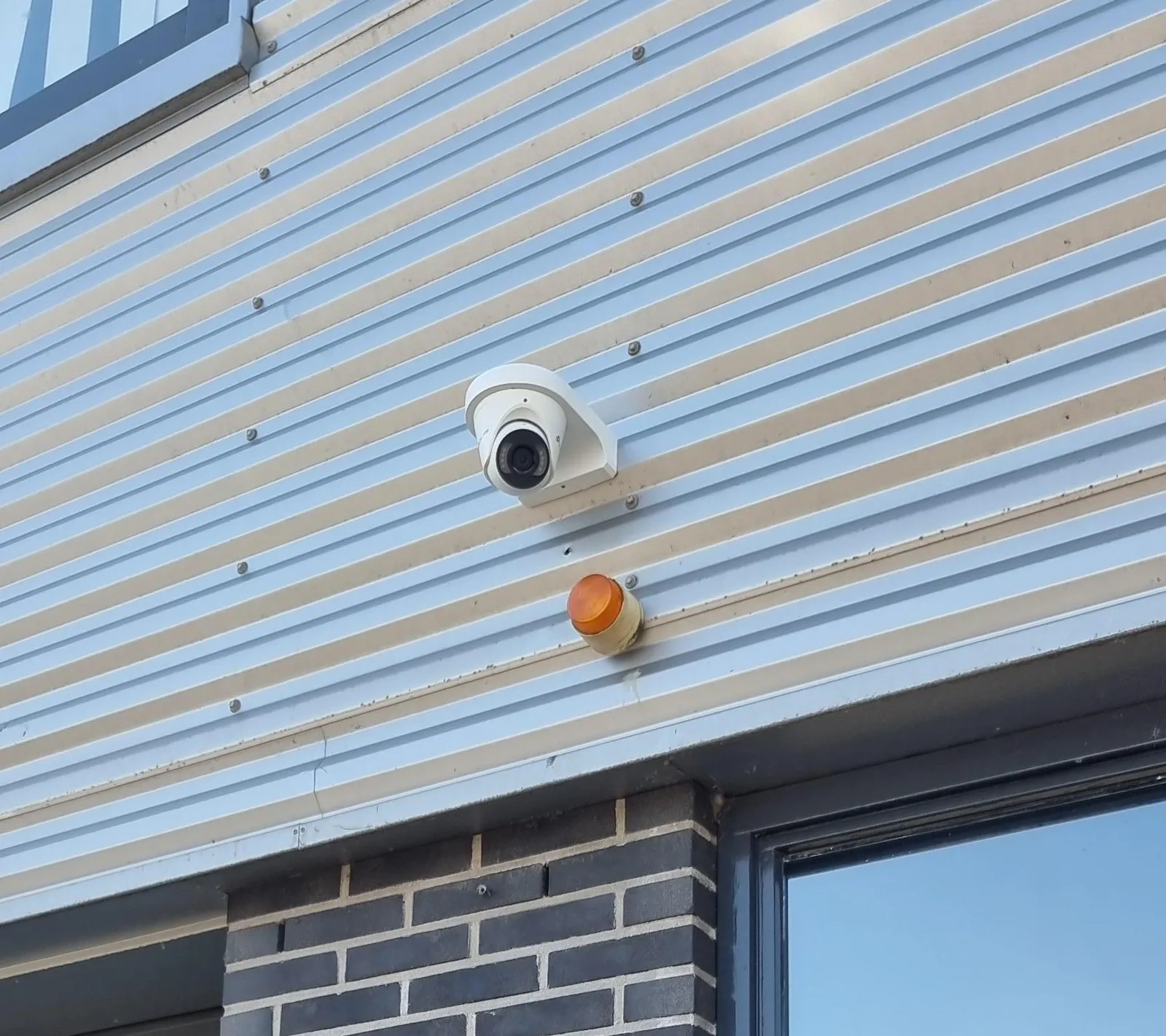 Witte VIGI InSight S485 op een lichte damwandgevel boven een pui van donkere steen